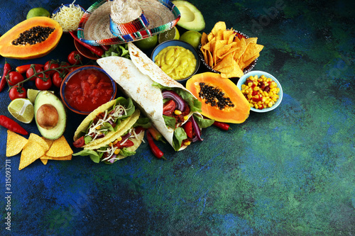 Mexican food, including tacos, guacamole, nachos and pepper on rustic table