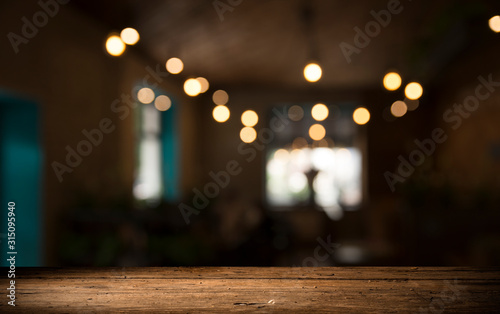 Empty wood table top on blur light gold bokeh of cafe restaurant in dark background