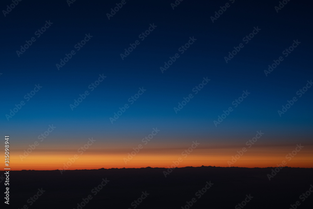 Beautiful view of sunset sky above clouds from airplane.