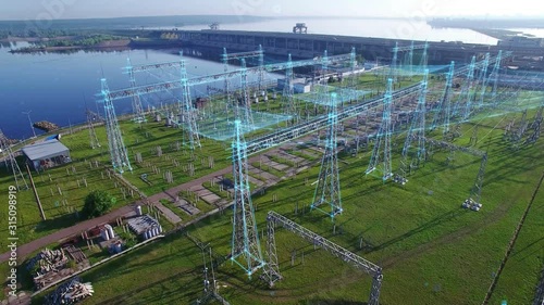 An aerial view a hydroelectric power station with infographic power flows motion graphics. Electric substation with tall pylons and hog voltage distribution cables. Early morning spring summer sun.