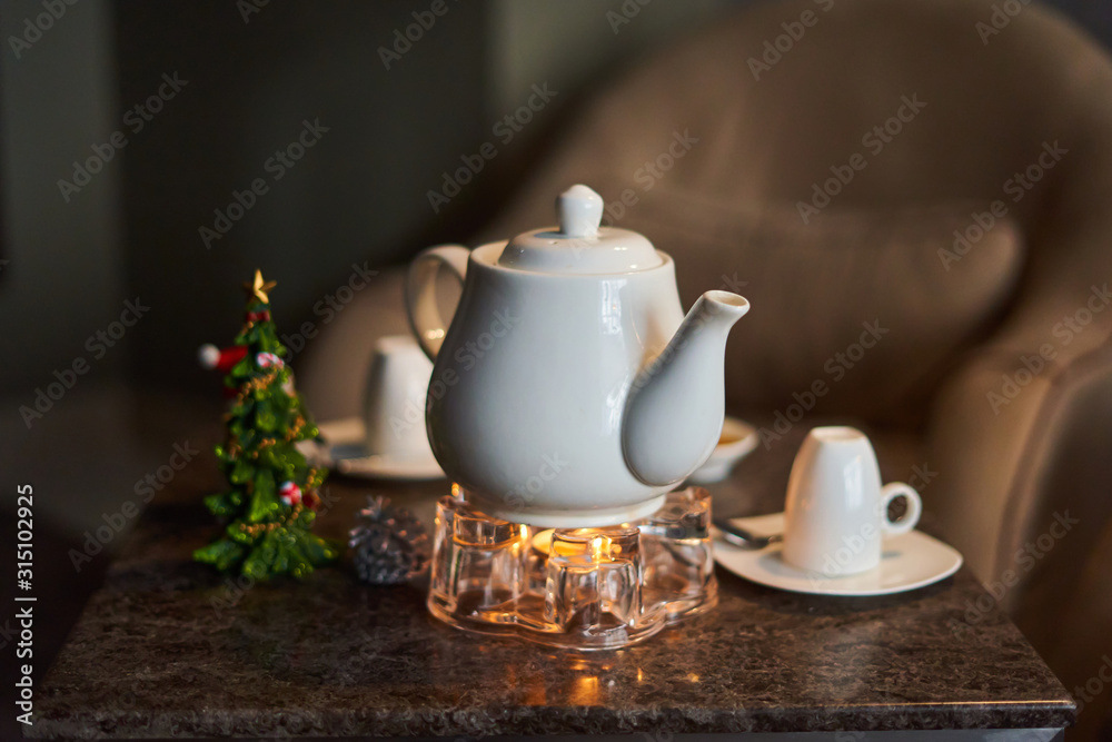 Relaxation area in the spa, drink tea, on the table there is a white teapot, in the background a Christmas tree and an inverted white mug Relaxation area in the spa, drink tea, on the table there is a white teapot, in the background a Christmas tree and an inverted white mug