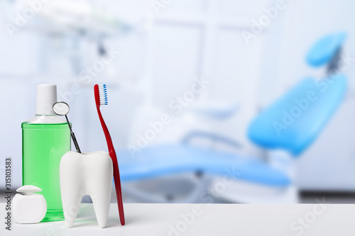 Dental health and teethcare concept. Dental mirror in white tooth model near mouthwash  toothbrush and dental floss against dental office and chair background