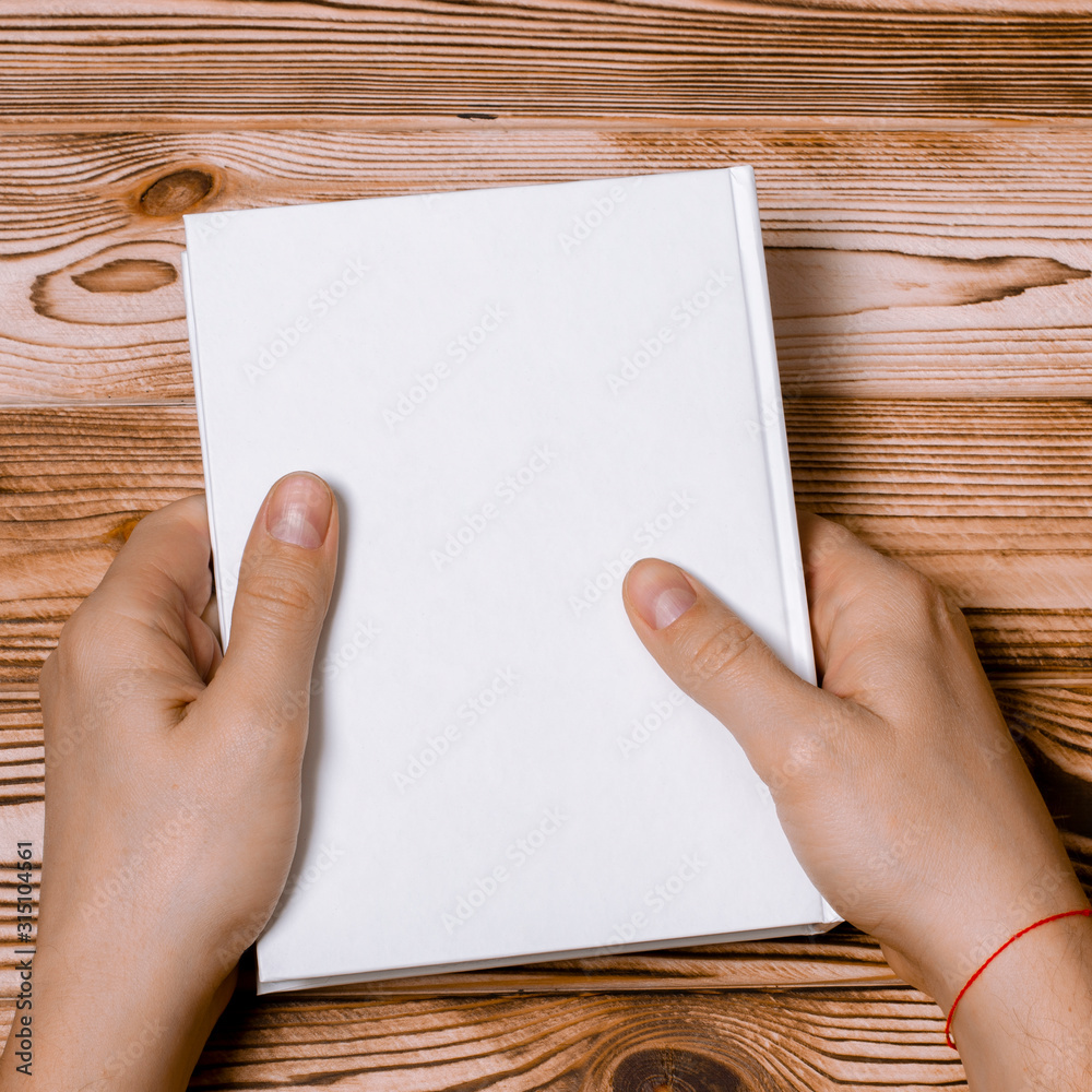 Men's hands holding closed book with blank cover on light background