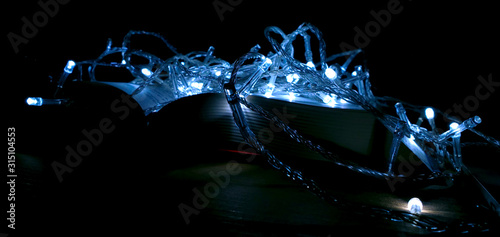 Stacks of books with a glowing garland. Christmas decor. Background for Christmas card. Soft focus