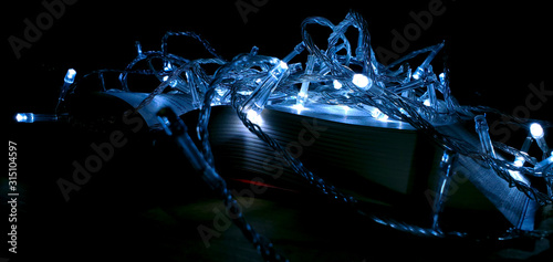 Stacks of books with a glowing garland. Christmas decor. Background for Christmas card. Soft focus