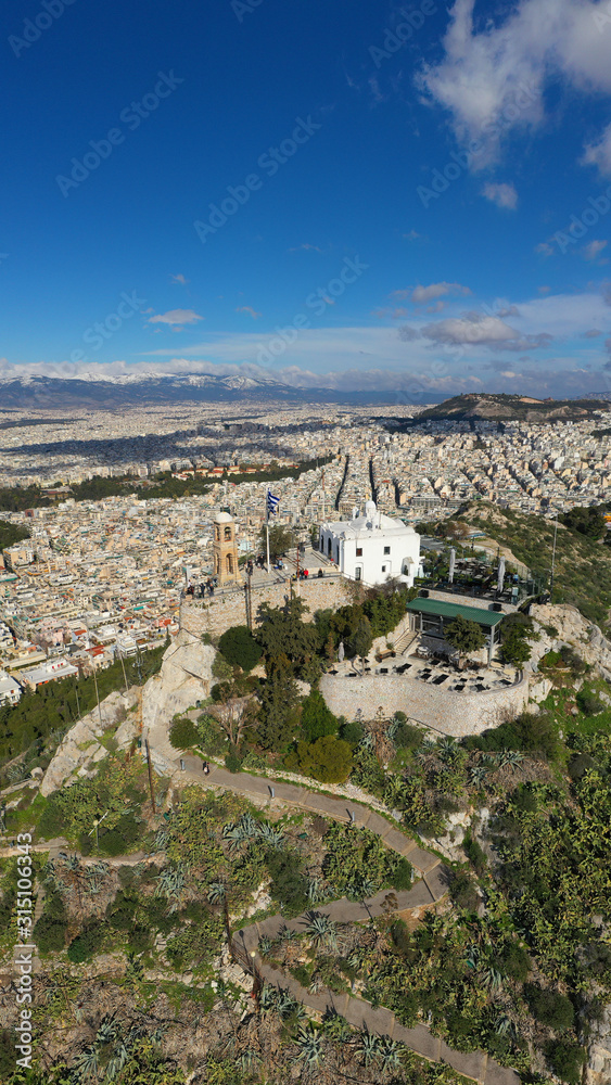 Aerial drone photo of iconic chapel of Saint George on top of Lycabettus hill with beautiful deep blue sky and clouds, Athens, Attica, Greece