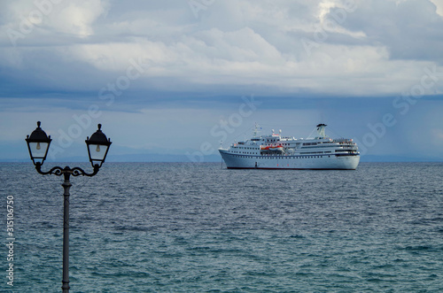 Classic small cruiseship or cruise ship liner Ocean Majesty of Majestic Cruises with street lantern in foreground on blue sea with blue sky and low clouds photo