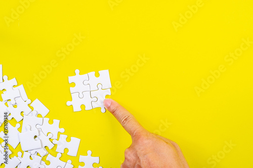 Jigsaw and hands on the yellow concept background