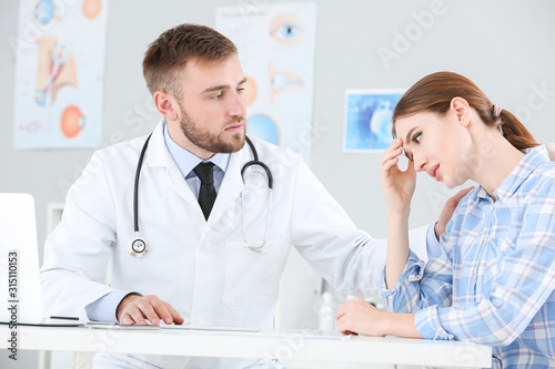 Male doctor calming sad fem...