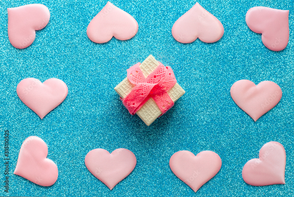 Fototapeta premium Valentines day pattern background flat lay pink hearts and a gold gift box with rose ribbon on a glittering classic blue background with copy space. love wedding romantic concept, minimal top view