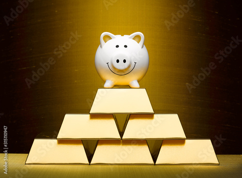 Smiling piggy bank on top of stacked gold bars