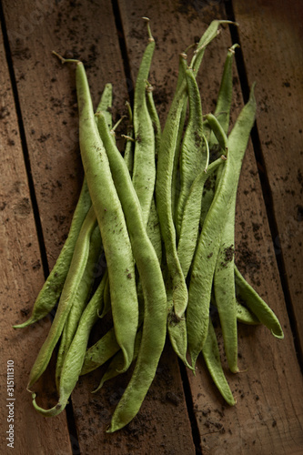 Still life close up fresh, organic, healthy, rustic, dirty green bean pods on wood photo