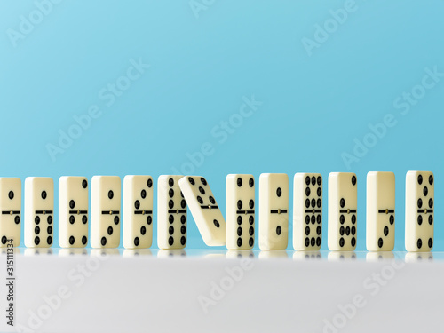 Falling in domino in a row on blue background photo