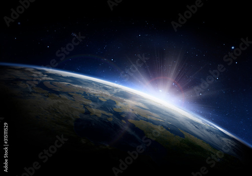 Sunlight ascending over Earth in outer space photo