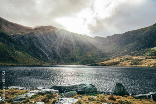 Sun shining over tranquil mountains and lake, Snowdonia NP, UK