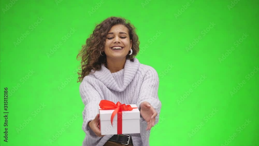 Afro-American woman is holding giftbox with red ribbon and is giving it to you. Best wishes. Close up. Copy space. Afro-American woman is holding giftbox with red ribbon and is giving it to you. Best wishes. Close up. Copy space.