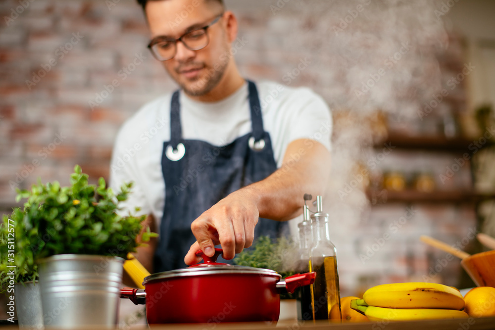 Young man cooking pasta. Chef preparing pasta in modern kitchen Young man cooking pasta. Chef preparing pasta in modern kitchen