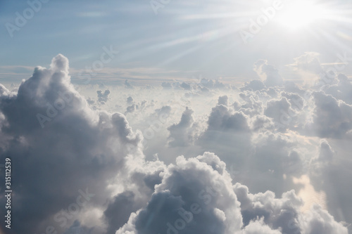 Aerial view sunbeams over fluffy clouds in sky © Martin Barraud/Caia Image