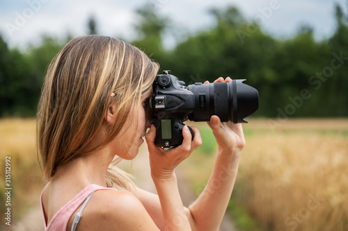 Profile view of young woman taking a photo of nature