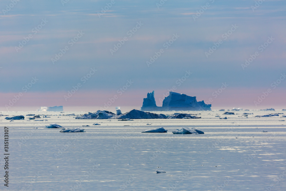 Melting icebergs over tranquil Atlantic Ocean Greenland Melting icebergs over tranquil Atlantic Ocean Greenland