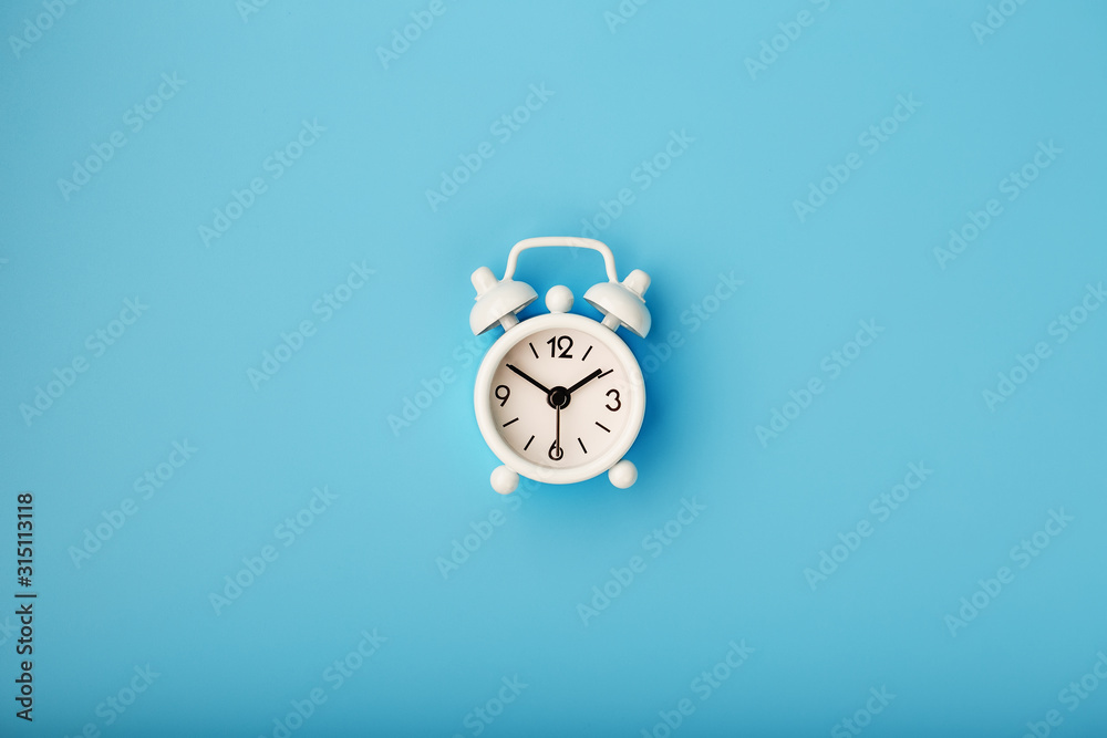 White retro alarm clock on blue background. Concept of time with free space for text. White retro alarm clock on blue background. Concept of time with free space for text.