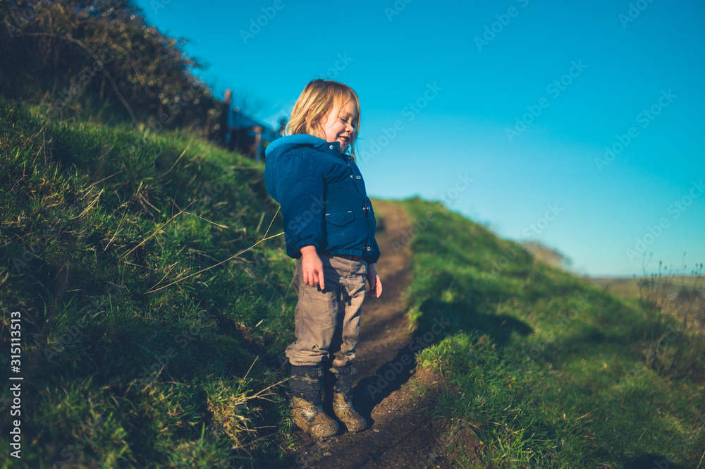 Naklejka premium Little toddler standing on hillside in winter