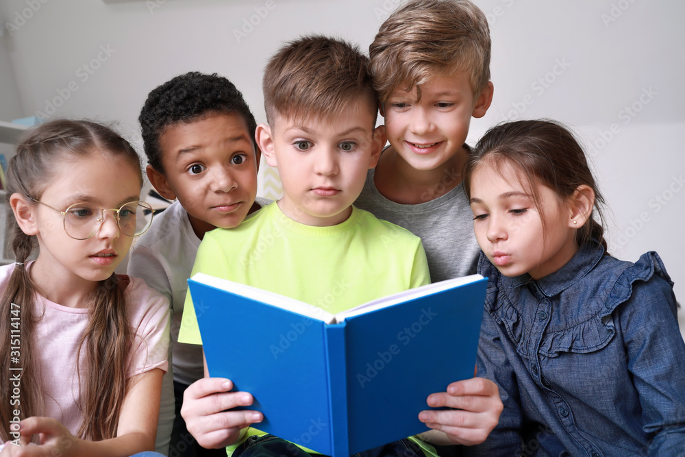 Surprised little children reading book indoors Surprised little children reading book indoors