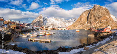 Panoramic view of Hamnoy, cozy fishing village in Lofoten Islands, Northern Norway. Scenic landscape with mountains, houses, boats, blue cloudy sky and reflection in the water, travel background © larauhryn
