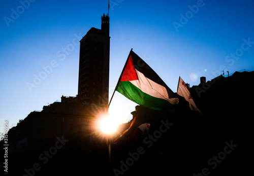 Photos Silhouette of raised Palestinian flag waving against the sun at sunset during a demonstration