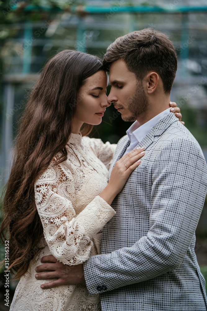 Romantic couple, bride and groom posing in a greenhouse against the background of plants in the garden. Advertising space Romantic couple, bride and groom posing in a greenhouse against the background of plants in the garden. Advertising space