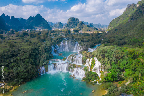 Massive hidden waterfall surrounded by mountain with blue clean water. Paradise on the border between China and Vietnam. Ban gioc waterfall, Detian. photo