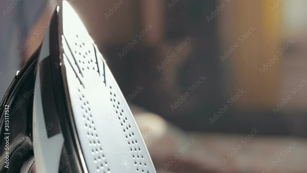 Iron with steam and water stream close-up. Ironing clothes on ironing board. Iron with steam and water stream close-up. Ironing clothes on ironing board.