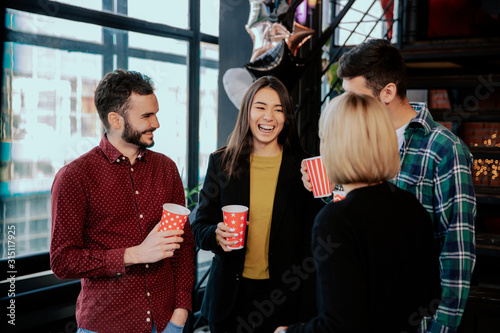 In a modern office center group of multiethnic workers while have a coffee break have a friendly conversation smiling and enjoying the coffee