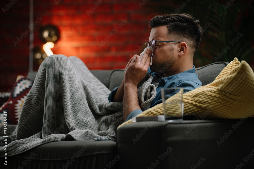 Fototapeta premium Young sick man sitting on sofa.