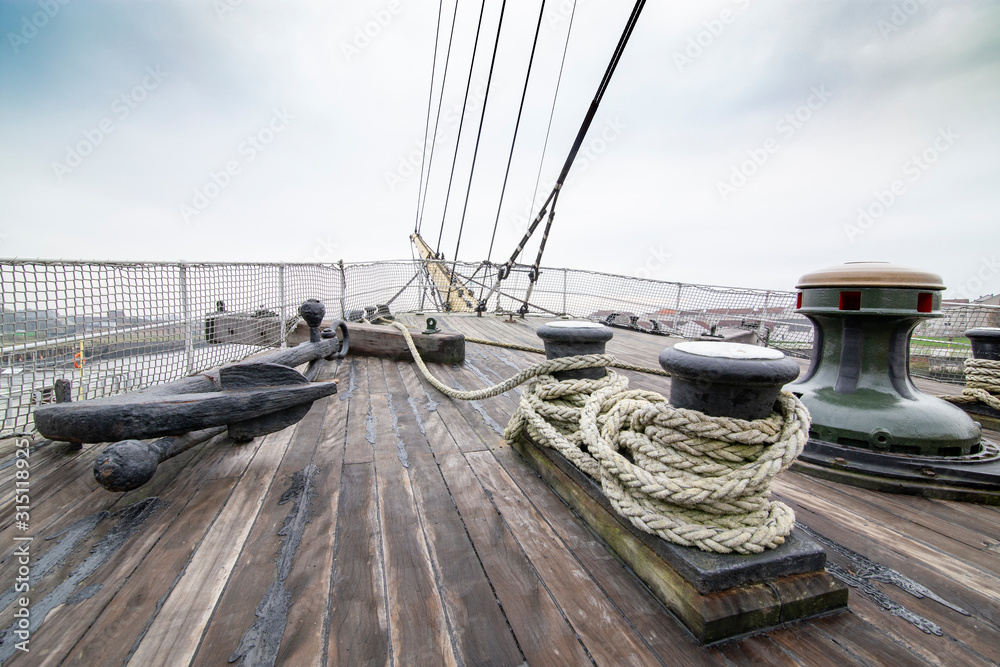 Old sail ship with wooden deck and its equipment; ropes, anchor, capstan.  Stock Photo
