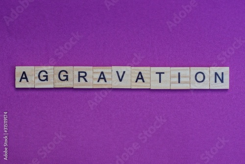 word aggravation from small gray wooden letters lies on a lilac background