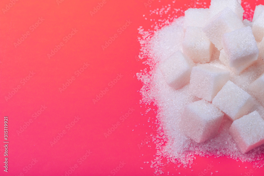 Cubes of white sugar and granulated sugar on an pink background, close-up Cubes of white sugar and granulated sugar on an pink background, close-up