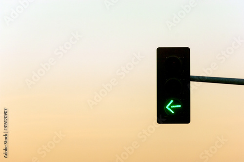Traffic light on crossroads with green light arrow and sunset on the background #315120907