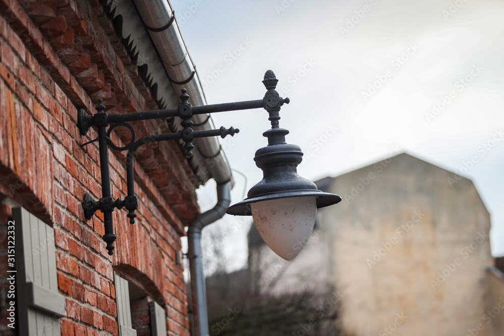 Small dirty lantern hanging out of old renovated orange brick house. Small dirty lantern hanging out of old renovated orange brick house.