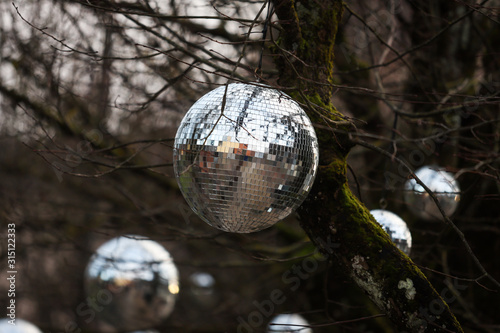 Discoball hanging on naked tree as a Christmass decoration.