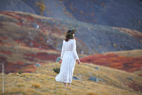 girl in a white dress walks on a background of mountains