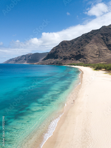 Man walking on the beach - Tropical paradise beach with white sand and mountain background travel tourism wide panorama background. Hawaiian beach. Oahu.