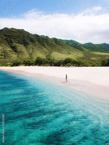 Man walking on the beach - Tropical paradise beach with white sand and mountain background travel tourism wide panorama background. Hawaiian beach. Oahu.