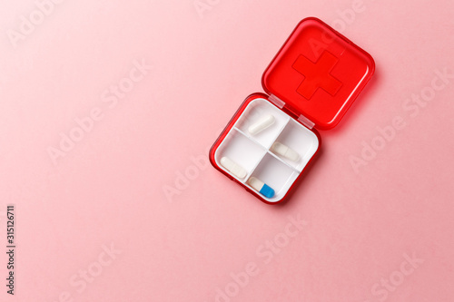 Dose pill box with medical pills on pink background. Top view. Flat lay. Copy space. Pharmaceutical medicine pills, tablets and capsules. Medicine concepts. Trendy pastel color