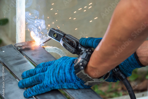 The welder is welding the metal plate to the metal frame of the swing. To repair the part of the seat to return to normal use...