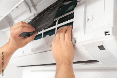 Male technician repairing air conditioner indoors, closeup