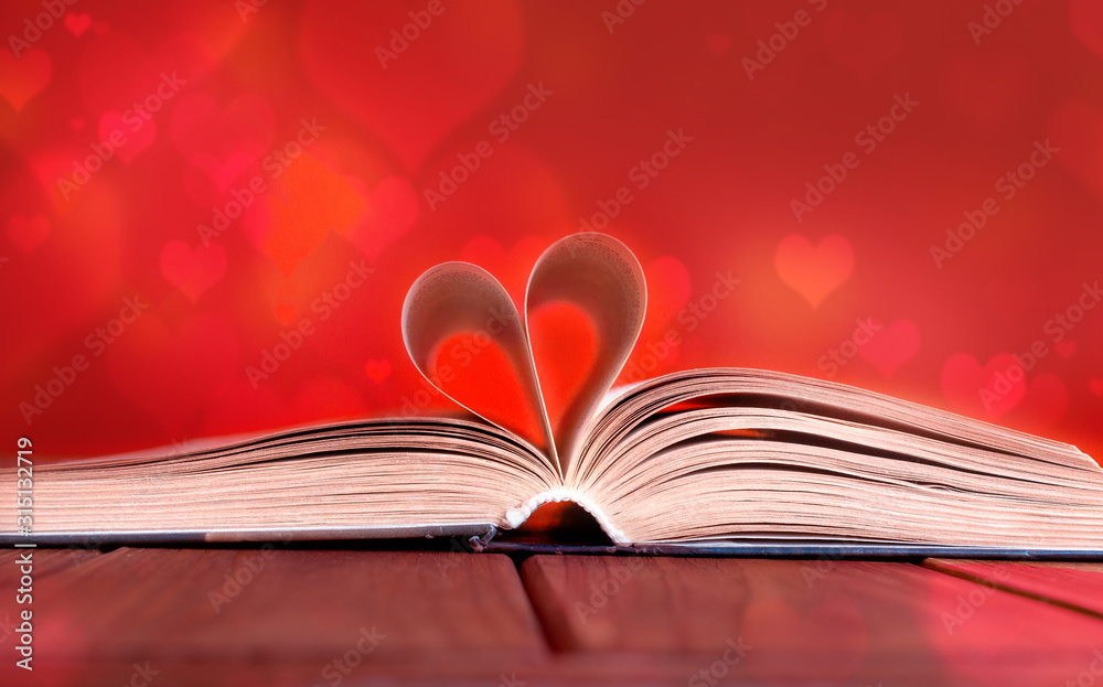 Open book on wooden table on red background Open book on wooden table on red background