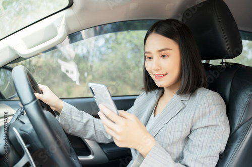 Asian woman talk by mobile calling texting and looking on a cellular phone while sitting in her car, driving under the influence, the driver is safely talking by smartphone in a car concept © Have a nice day 