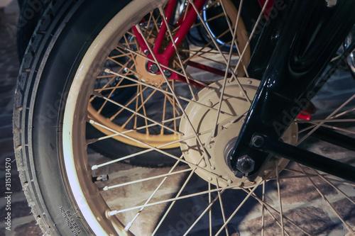 The detail of the old motorcycle with part of the frame, suspension and front Wheel with lacing. 
