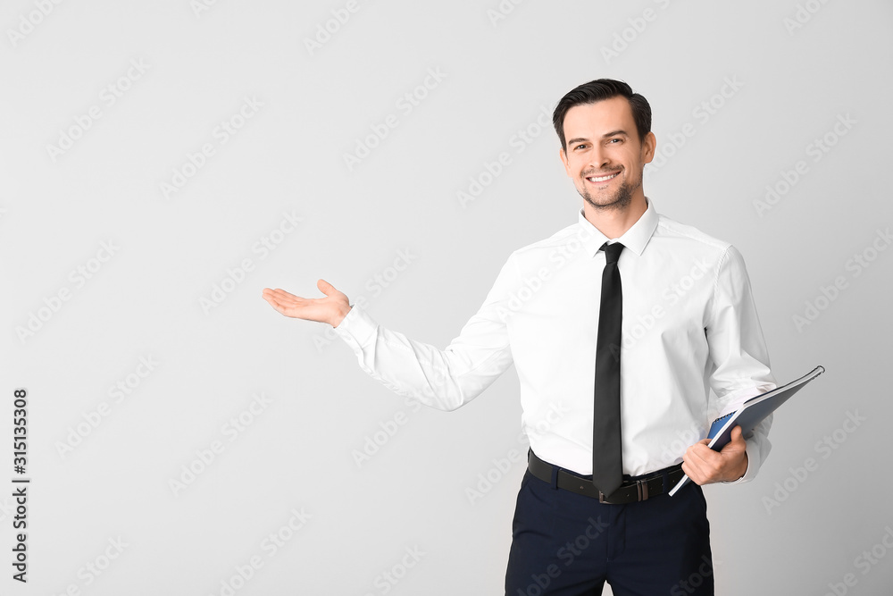 Male real estate agent showing something on light background Male real estate agent showing something on light background